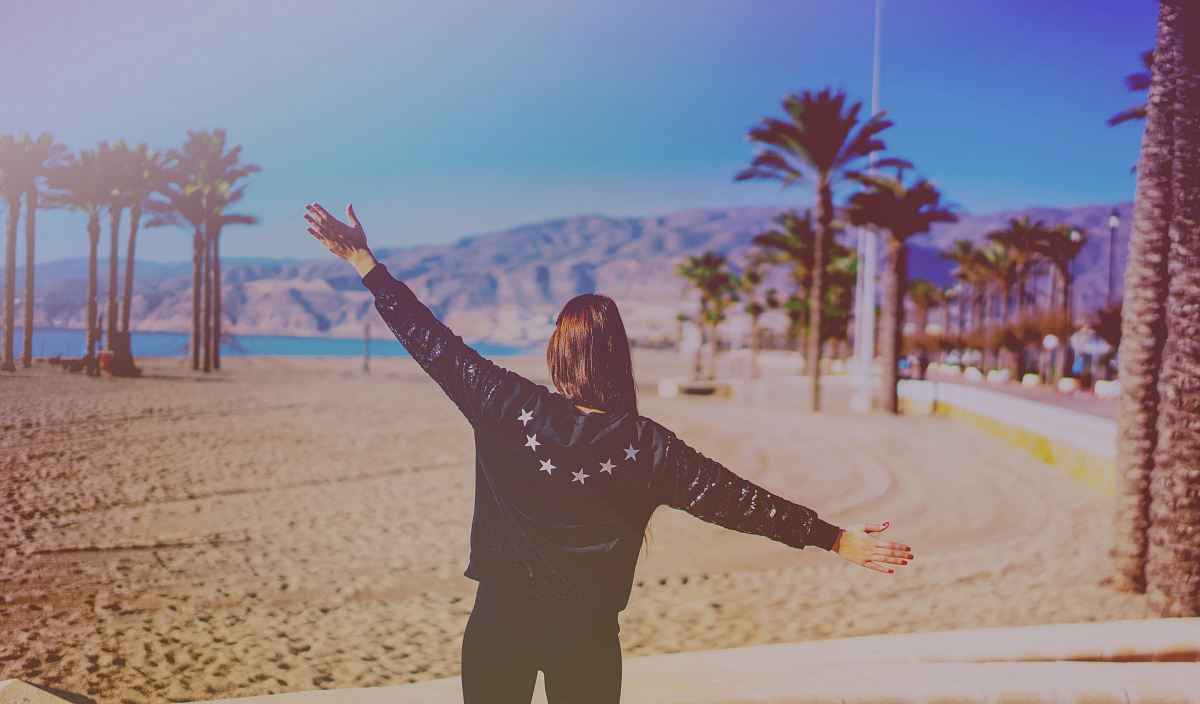 woman in black leather jacket beside beach shore during daytime